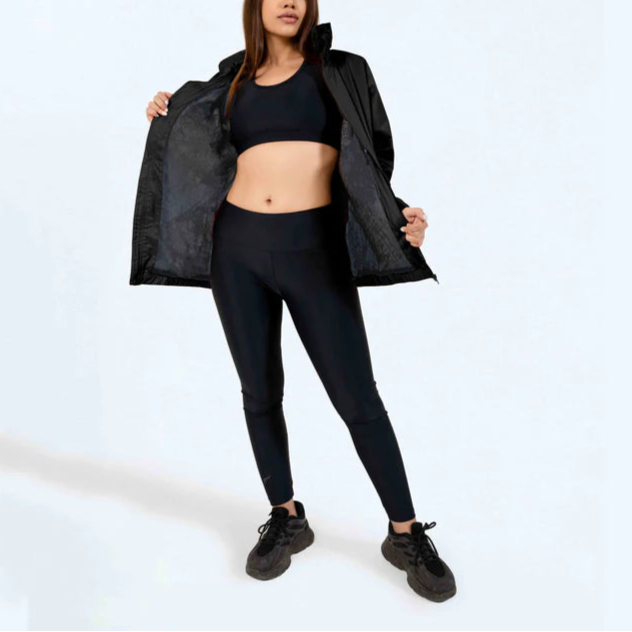 Woman wearing a black athletic outfit with a jacket on a white background