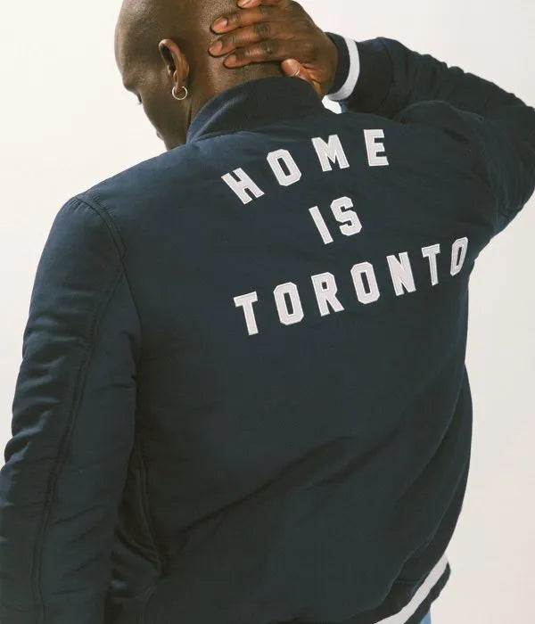 Person wearing a navy blue jacket with 'HOME IS TORONTO' text on the back.