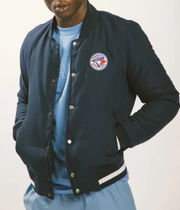 Person wearing a navy blue varsity jacket with a logo on a white background